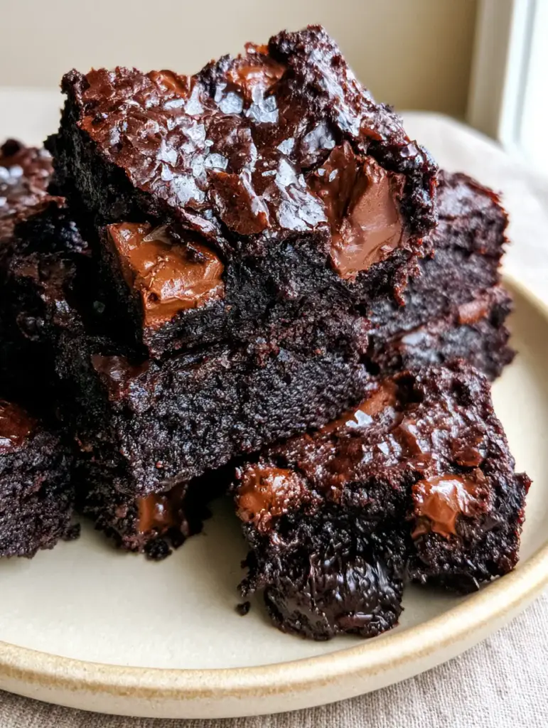 Zucchini Brownies: The Secret to an Ultra-Fudgy Dark Chocolate Masterpiece 1 A single Zucchini Brownie pulled apart to reveal a molten, gooey center with visible chocolate chunks and salt crystals.