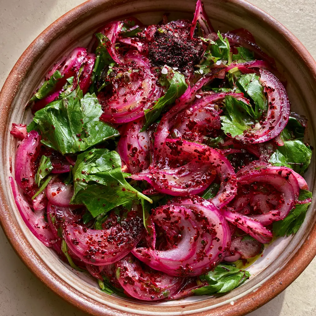 Turkish onion salad: The Authentic Sumac Onion Recipe (Sumaklı Soğan) 2 High-angle smartphone photo of Turkish onion salad showing translucent red onion half-moons and ruby-red sumac dusting.