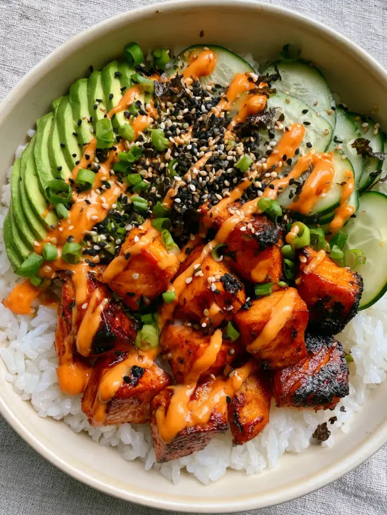 Spicy Salmon Sushi Bowls with Crispy Air-Fried Glazed Bites 1 Full assembly of spicy salmon sushi bowls with cucumbers, edamame, and fanned avocado on grey linen.