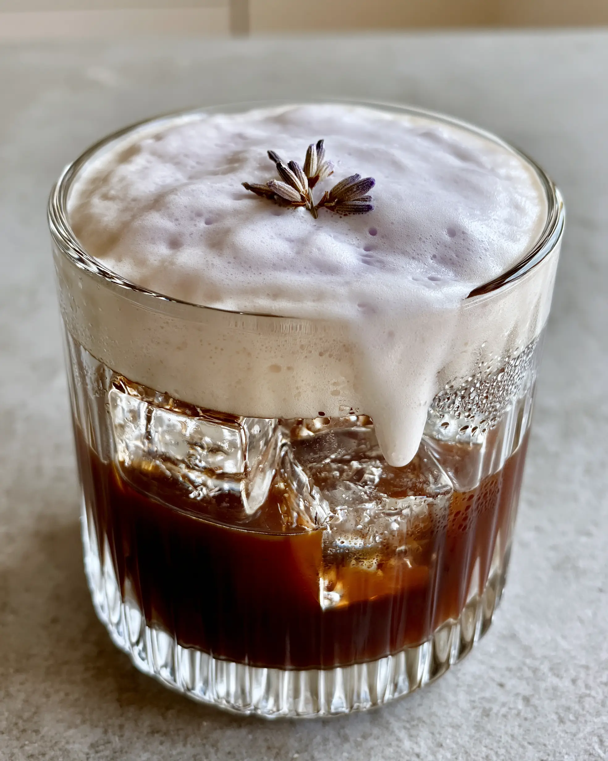 Lavender Cold Foam Iced Espresso: A Barista-Style Morning Ritual 3 A handheld smartphone photo of a Lavender Cold Foam drink on a concrete countertop in morning light.