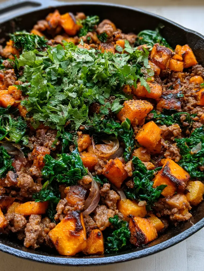 Ground Beef Sweet Potato Bowl with Wilted Kale and Caramelized Onions 2 Overhead macro shot of seared ground beef and caramelized sweet potato cubes in a skillet. (ground beef sweet potato bowl)