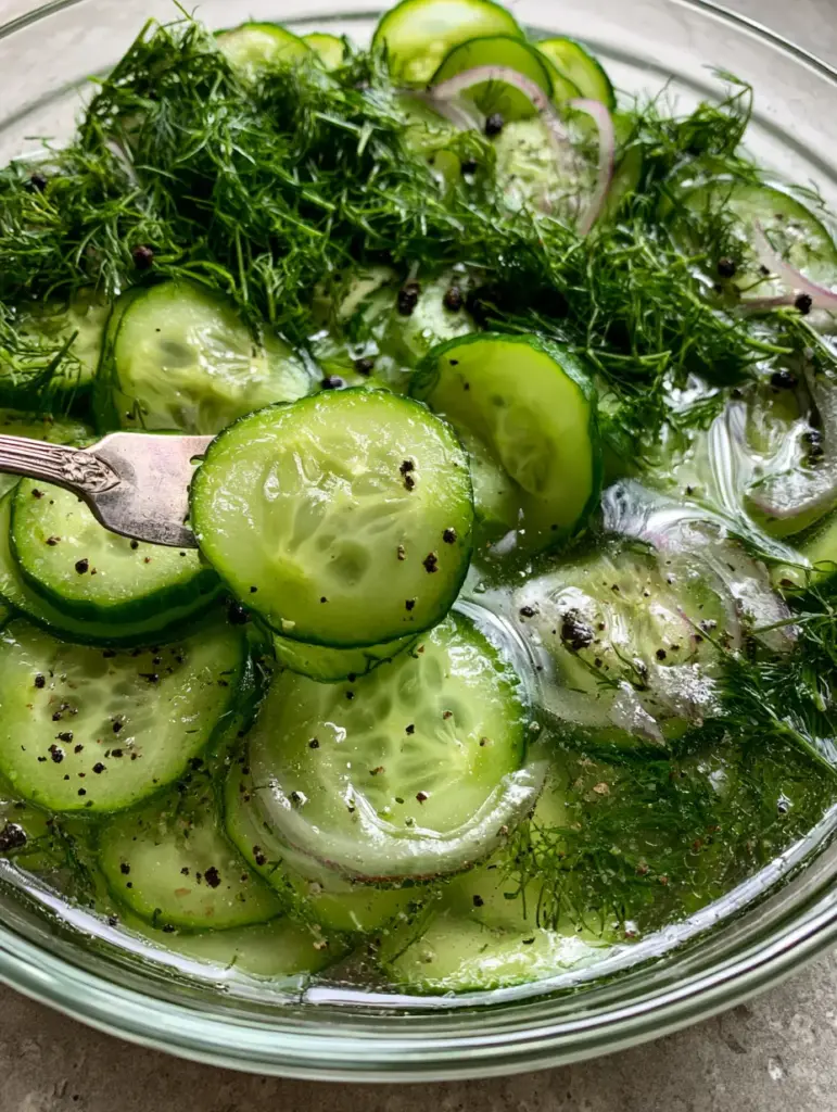 Cucumbers and Onions in Vinegar: The Ultimate Crisp Summer Salad 1 A vintage silver fork lifting a semi-translucent cucumber slice from a glass bowl. (Cucumbers and onions in vinegar)