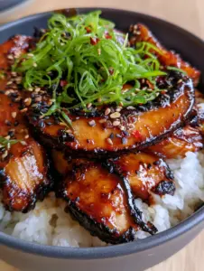 Close up shot of thick seared mushroom slices in a Teriyaki mushrooms and rice bowl with sesame seeds.