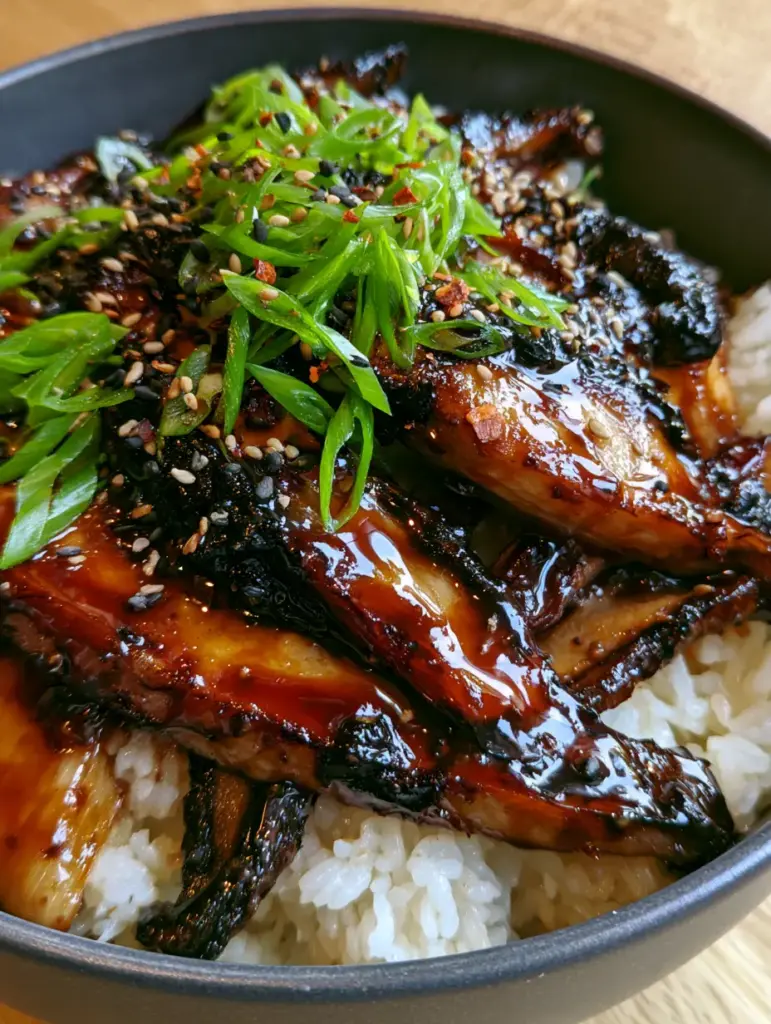 Steaming jasmine rice base of a Teriyaki mushrooms and rice bowl topped with vibrant green scallions.
