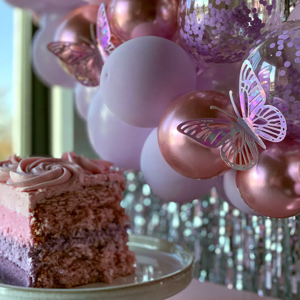 Pink and purple birthday party ideas: The Ultimate Ombre Layer Cake Guide 1 A slice of moist pink and purple ombre cake with vanilla buttercream swirls on a white ceramic plate against a silver tinsel backdrop.