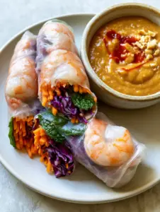 Extreme macro close-up of three plump Vietnamese rice paper rolls revealing vibrant layers of orange carrots, purple cabbage, and emerald mint. (Vietnamese Rice Paper Rolls Recipe)