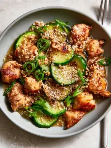 Close up of golden-brown chicken chunks and crisp charred zucchini with sesame seeds. (zucchini stir fry)