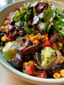 A vibrant Mexican Bean Salad with glistening black beans, red kidney beans, and bright golden charred corn in a light stoneware bowl.