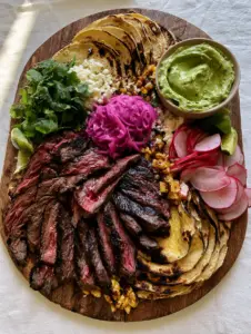 Overhead view of a vibrant taco spread with charred corn, purple onions, and seared steak—a perfect example of fun dinner ideas.