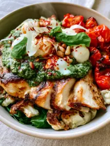 Close up photo of seared chicken breast with golden edges in a Chicken Pesto Parm Bowl.