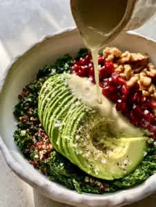 A macro top-down view of a Glass Skin Beauty Bowl with deep emerald kale and glossy tahini drip (glowing skin tips).