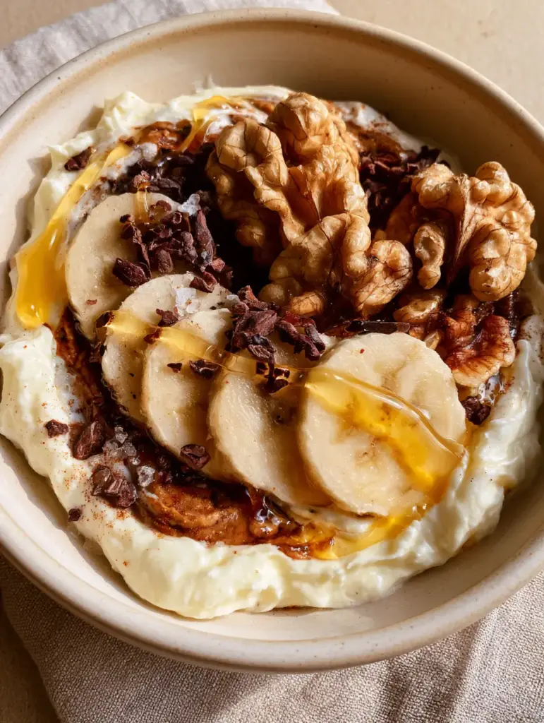 A glistening honey drizzle over banana slices and walnuts in a midnight snacks bowl.