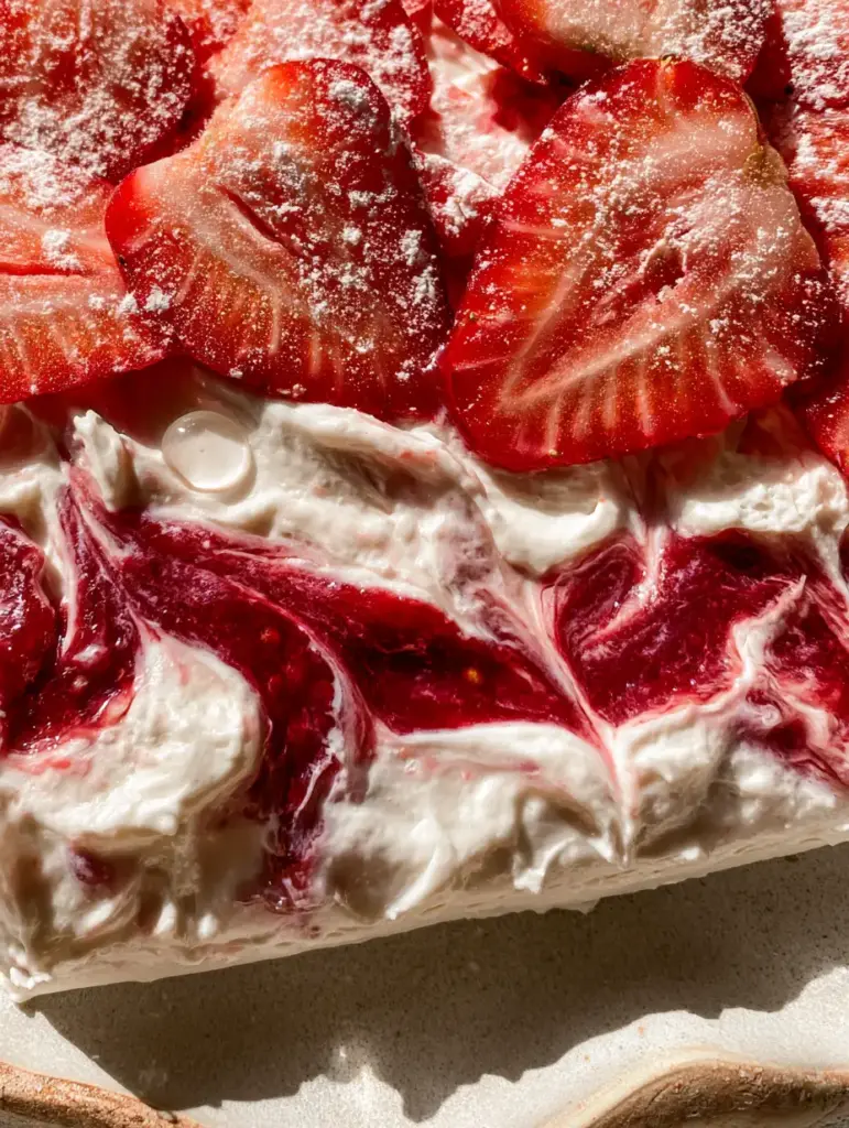 Easy Snack Idea: High-Protein Strawberry Greek Yogurt Bark 1 A handheld smartphone photo of yogurt bark on a matte ceramic plate, showing seed patterns in strawberries.