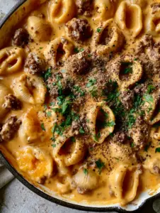 Top-down shot of creamy beef and shells recipe with deep orange sauce pooling in pasta shells.