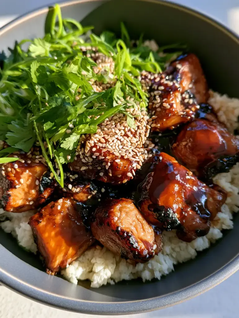 Paleo Chicken Teriyaki with Sticky Mahogany Glaze and Cauliflower Rice 1 Gourmet Paleo Chicken Teriyaki with charred edges and sesame seeds in a charcoal bowl.