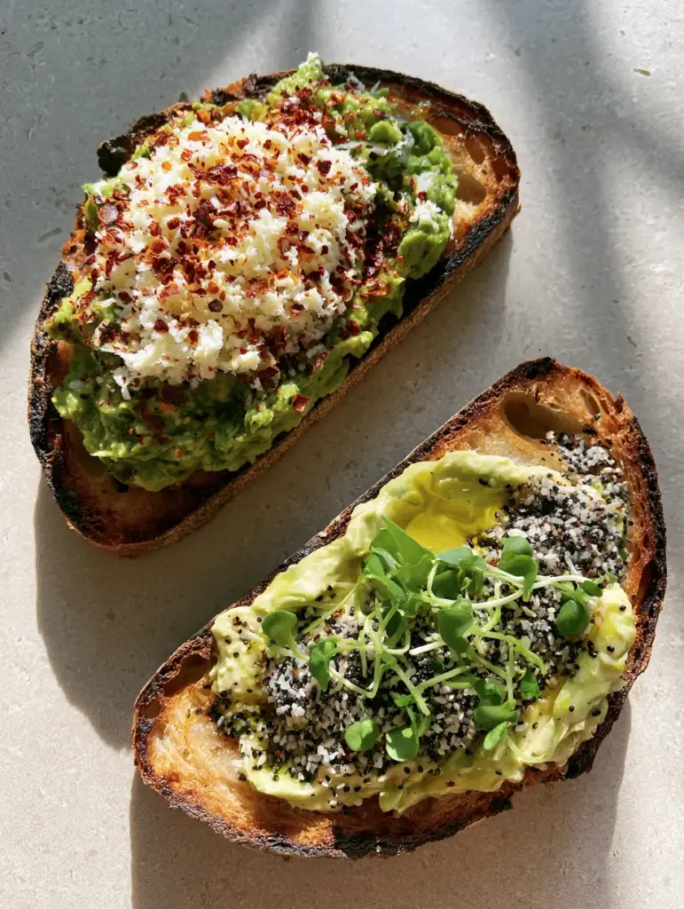Breakfast Avocado Toast with Finely Grated Egg and Chili Flakes 1 Detailed shot of everything bagel seasoning and micro-cilantro on breakfast avocado toast.