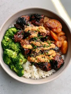 Close up of charred honey garlic steak tips with a creamy sauce drizzle, a staple of healthy dinners for picky eaters.