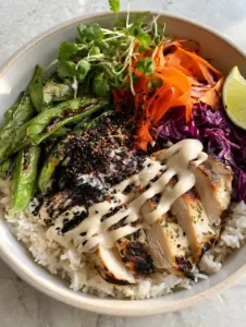 Top down view of a chicken grain bowl with grill marks and zig-zag tahini dressing for healthy dinners.