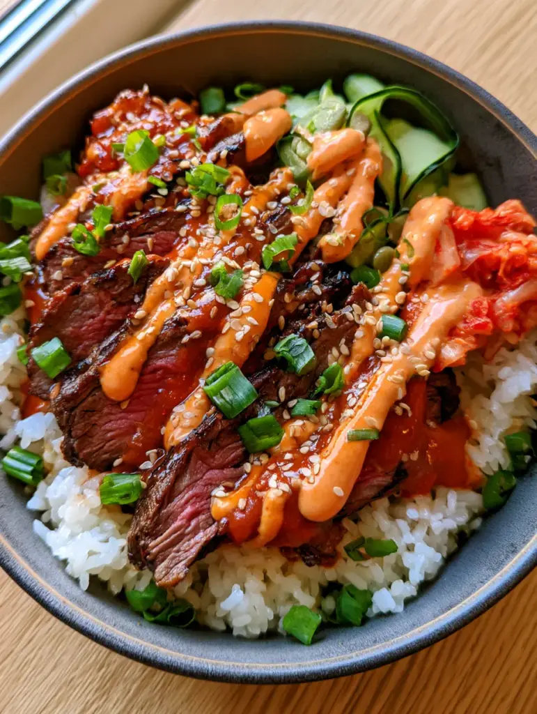 Korean Bbq Steak Bowls served in a charcoal ceramic bowl on a light oak surface.