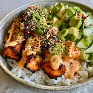 Close up macro detail of charred air-fried salmon flakes in a textured ceramic bowl. (Spicy salmon bowls)