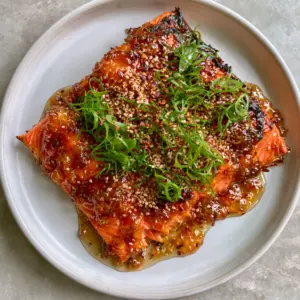Close-up of flaky Honey-garlic steelhead trout showing the moist texture and translucent honey glaze.