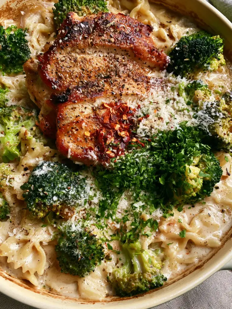 Creamy Chicken and Broccoli Bowties: The Ultimate Skillet Pasta Dinner 1 Deep golden-brown seared chicken breast slices on top of creamy pasta and forest green broccoli.