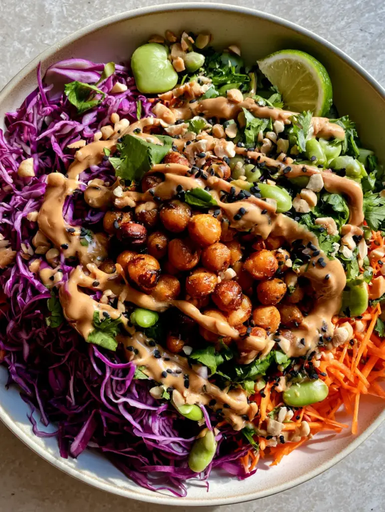 Crunchy Thai Chickpea Salad with Creamy Peanut Dressing 1 Overhead view of tan peanut dressing drizzled over purple cabbage and edamame for a Crunchy Thai Chickpea Salad.