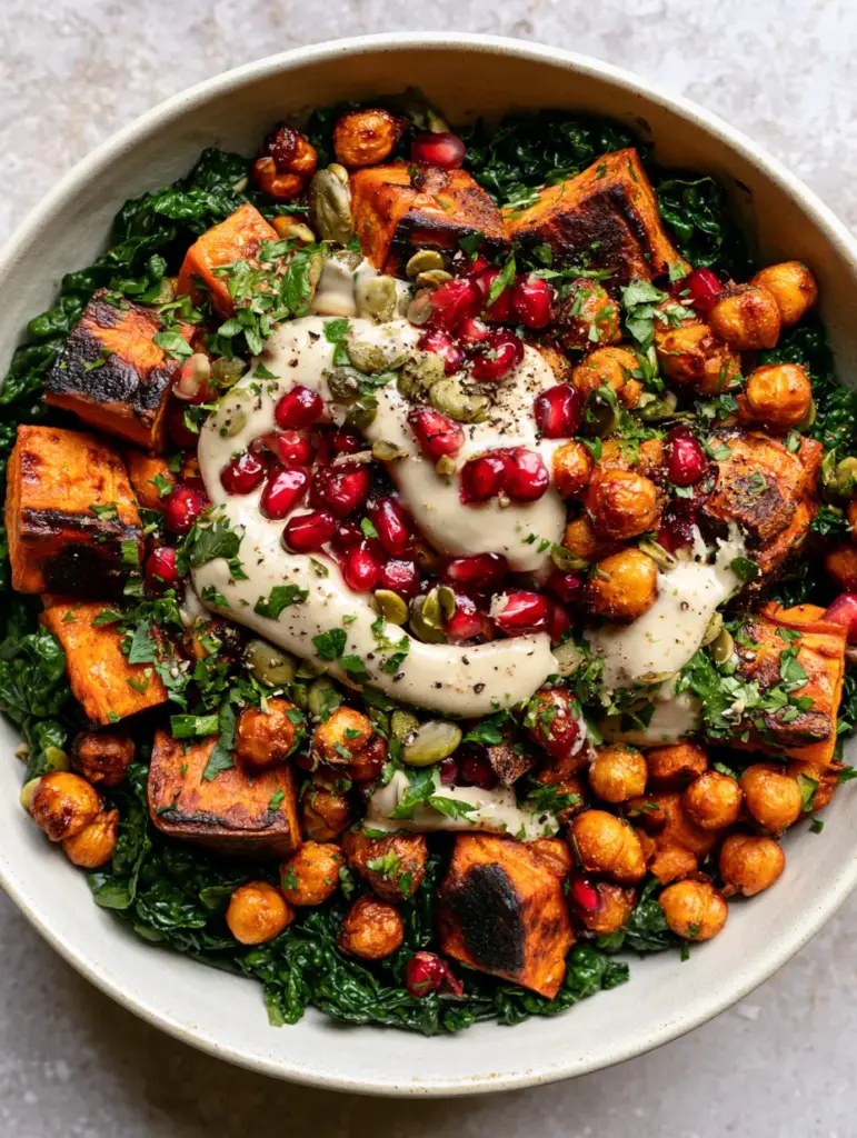 Sweet Potato and Chickpea Salad with Creamy Lemon Tahini Dressing 1 Detailed close-up showing thick ivory tahini dressing ribbons drizzled over massaged emerald kale and pomegranate arils in a sweet potato and chickpea salad.