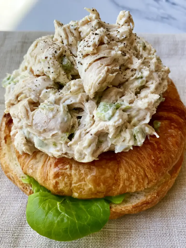 Chicken Salad Chick Recipe: The Ultimate Guide to the Signature Shredded Southern Classic 1 Side view of a toasted croissant sandwich with creamy chicken salad and bibb lettuce leaf. (Chicken Salad Chick recipe)