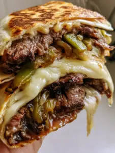 Extreme macro shot of a Philly cheesesteak quesadilla recipe showing charred ribeye and leopard spotting on the tortilla. (Philly cheesesteak quesadilla recipe)