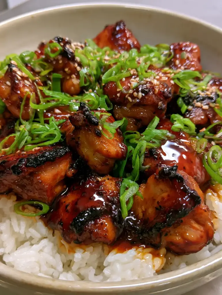Bourbon Chicken Recipe: The Ultimate Guide to Sticky, Charred Perfection 1 A handheld smartphone photo of bourbon chicken garnished with sesame seeds and green onions.
