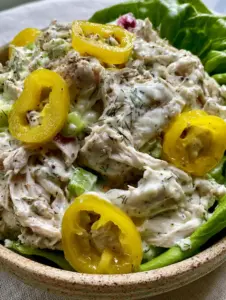 Extreme close-up of Pepperoncini Chicken Salad showing the thick white dressing, cracked black pepper, and glistening yellow pepperoncini rings.
