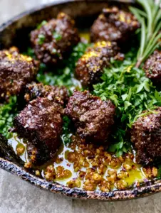 Macro close-up of seared steak bites with visible salt flakes and charred edges in butter. (Steak dinner)