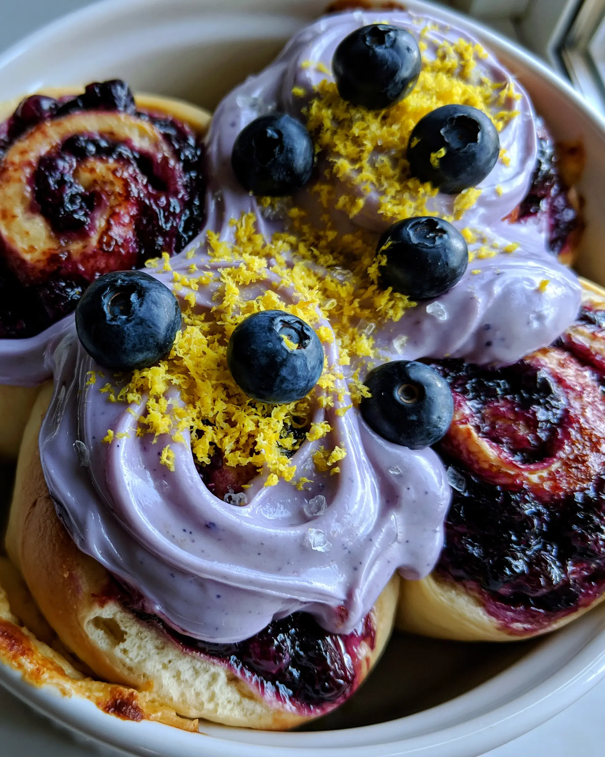Blueberry Cinnamon Rolls with Lavender Cream Cheese Frosting 3 Detailed close-up of pull-apart brioche dough spirals with bubbling dark purple blueberry preserves. (blueberry cinnamon rolls)