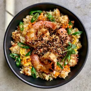 Close-up of dry-seared cauliflower rice grains with charred edges and plump shrimp. (Cauliflower Shrimp Fried Rice)