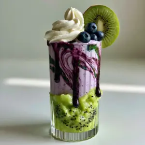 Handheld photo of a Blueberry Kiwi Frappuccino showing vibrant green kiwi puree and pastel violet blueberry layers.