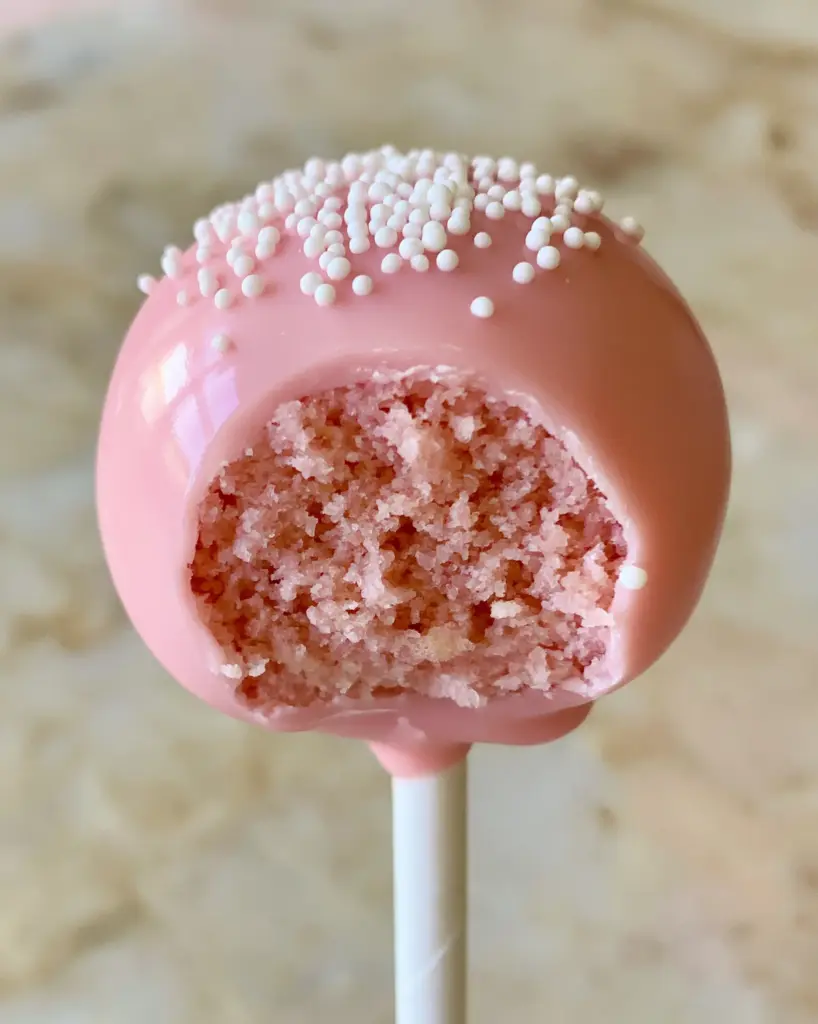 Cake Pop Flavors: The Ultimate Starbucks Copycat Pink Vanilla Recipe 1 A close-up of a pink cake pop with a bite taken out, revealing a moist pink crumb. (cake pop flavors)